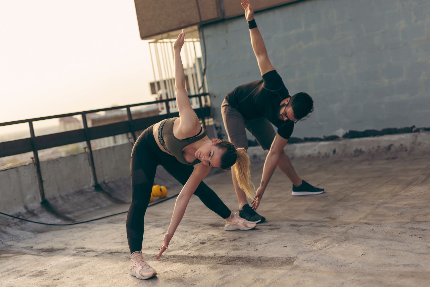 man and woman on the roof of a building. They doing a toe touch stretch, which is good for back pain relief